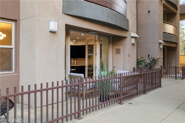 entrance to property with fence and stucco siding