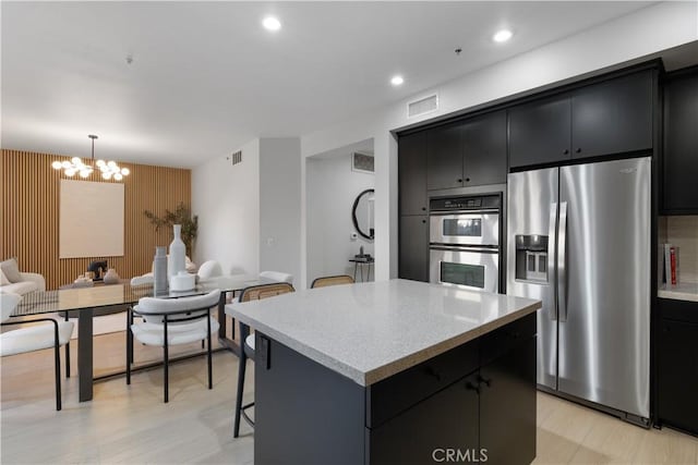 kitchen featuring a kitchen island, open floor plan, dark cabinets, a kitchen breakfast bar, and stainless steel appliances