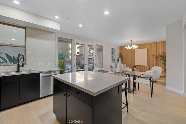 kitchen with a center island, a sink, dark cabinetry, dishwasher, and a kitchen breakfast bar