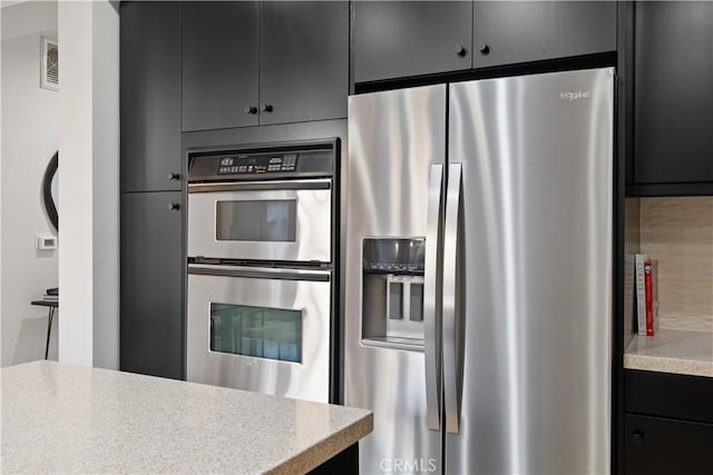 kitchen with visible vents, decorative backsplash, stainless steel appliances, dark cabinetry, and light countertops