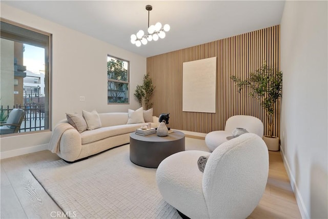 living room with baseboards, an accent wall, a chandelier, and wood finished floors