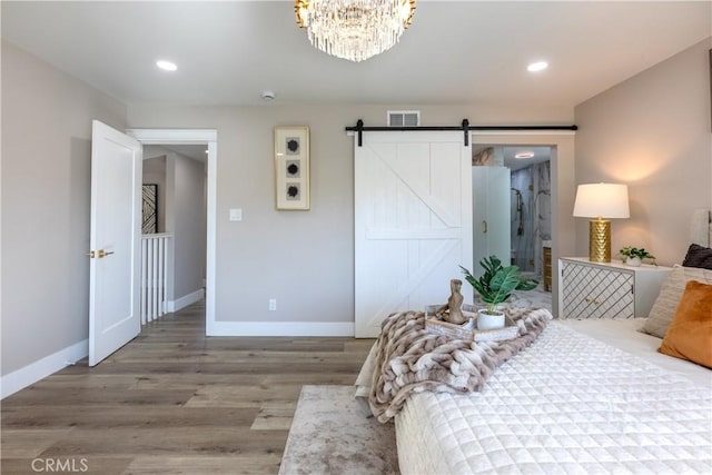 bedroom featuring a barn door, recessed lighting, wood finished floors, visible vents, and baseboards