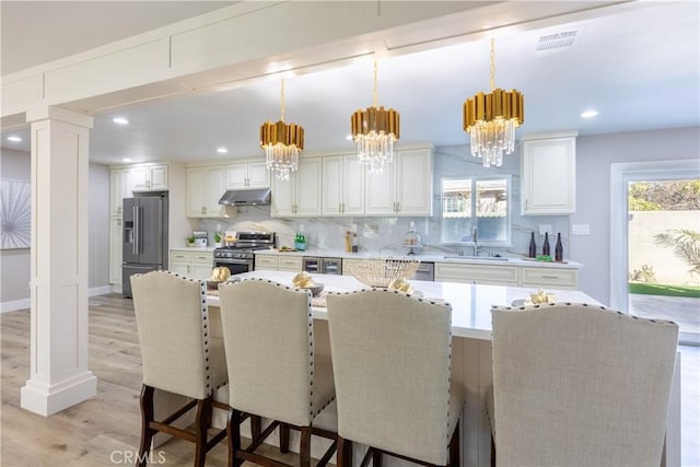 kitchen featuring visible vents, decorative backsplash, stainless steel appliances, under cabinet range hood, and a sink