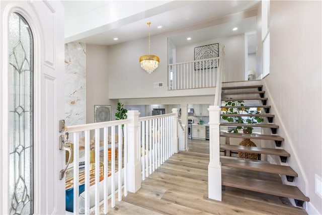 staircase featuring recessed lighting, visible vents, an inviting chandelier, and wood finished floors