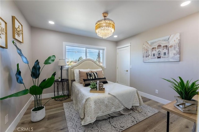 bedroom with recessed lighting, an inviting chandelier, wood finished floors, and baseboards