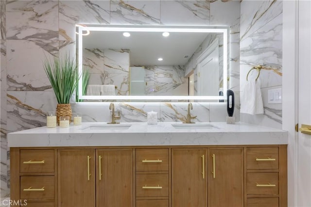 full bath with double vanity, stone wall, a sink, and recessed lighting