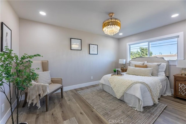 bedroom featuring baseboards, recessed lighting, wood finished floors, and an inviting chandelier