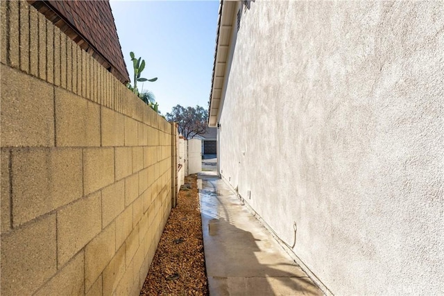 view of side of home featuring fence and stucco siding