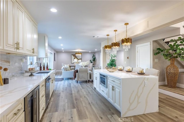 kitchen with wine cooler, recessed lighting, a sink, light wood-style floors, and open floor plan