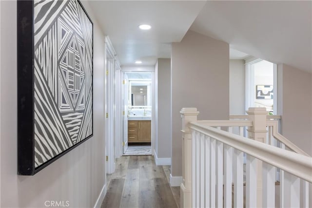 hall with recessed lighting, baseboards, an upstairs landing, and wood finished floors