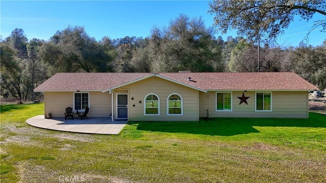 back of property with a patio, a yard, and roof with shingles