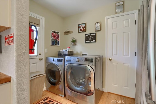 washroom with laundry area, washing machine and dryer, and light wood-style flooring