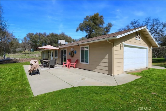 back of house with a garage, a patio area, and a lawn