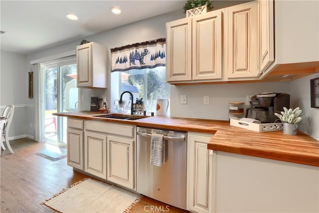 kitchen featuring wood counters, light wood-type flooring, stainless steel dishwasher, a sink, and recessed lighting