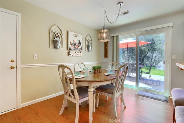 dining room featuring light wood-type flooring, visible vents, and baseboards