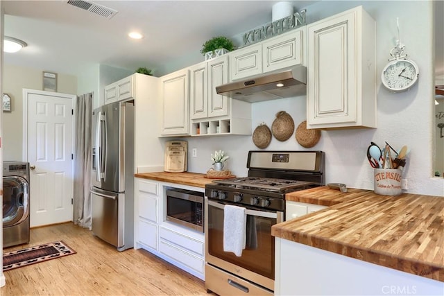 kitchen with appliances with stainless steel finishes, washer / dryer, wooden counters, and under cabinet range hood