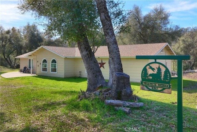 exterior space featuring a yard, a patio, and roof with shingles