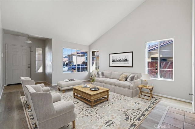 living room with a wealth of natural light, high vaulted ceiling, baseboards, and wood finished floors