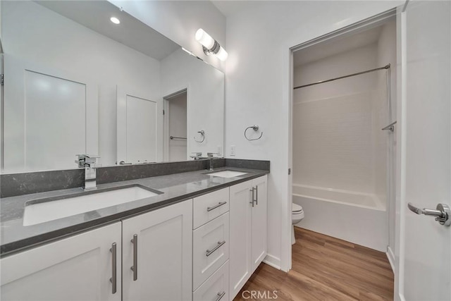 bathroom featuring double vanity, wood finished floors, a sink, and toilet