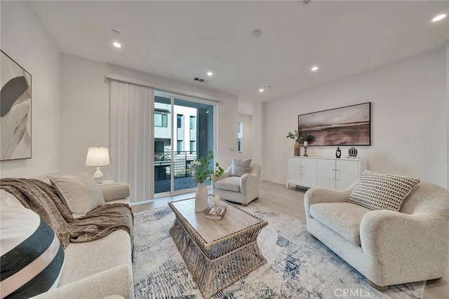 living area with baseboards, light wood-type flooring, visible vents, and recessed lighting