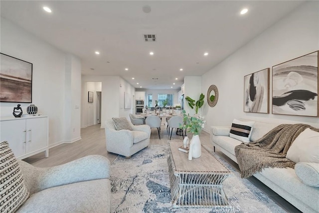 living area with light wood-type flooring, baseboards, visible vents, and recessed lighting