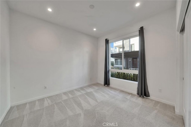 unfurnished room with recessed lighting, baseboards, and light colored carpet