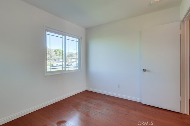 empty room with baseboards and wood finished floors