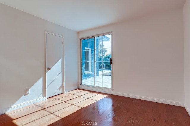 spare room featuring plenty of natural light, wood finished floors, and baseboards