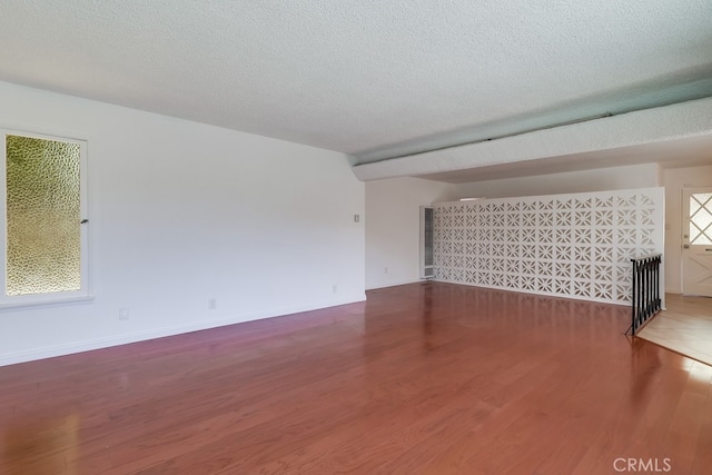 unfurnished living room featuring a textured ceiling and wood finished floors