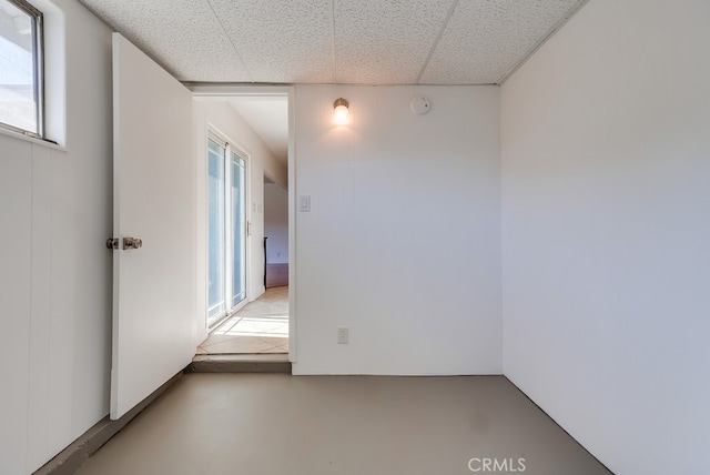 unfurnished room with a wealth of natural light, a paneled ceiling, and finished concrete flooring