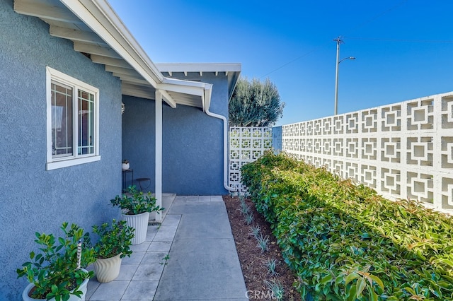 entrance to property featuring fence and stucco siding