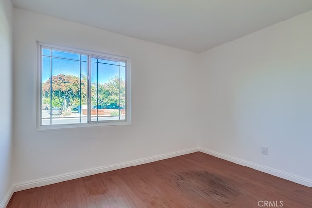 empty room featuring baseboards and dark wood finished floors