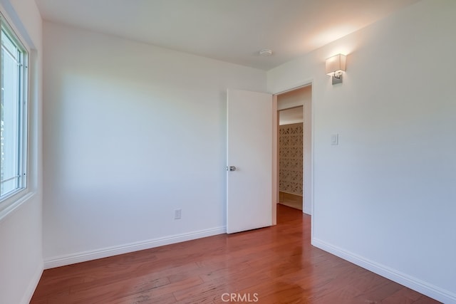 spare room with baseboards and wood finished floors