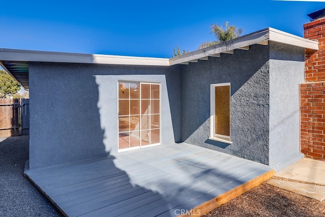 property entrance with fence and stucco siding