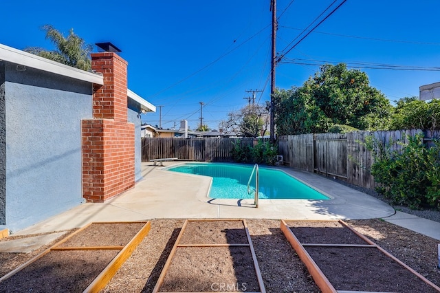 view of swimming pool featuring a garden, a fenced backyard, a patio area, and a fenced in pool