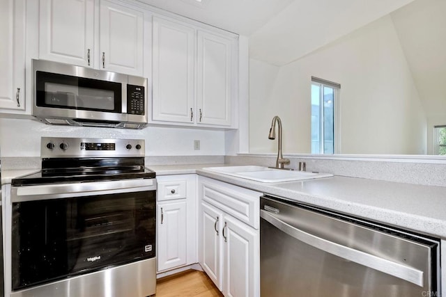 kitchen featuring stainless steel appliances, white cabinets, light countertops, and a sink