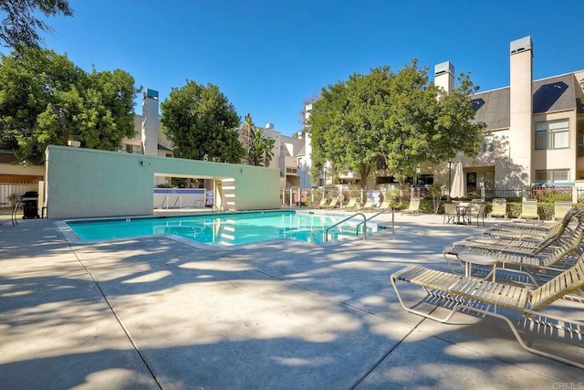 pool with a patio area and fence