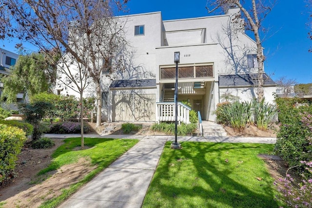 exterior space featuring a yard, stairs, and stucco siding