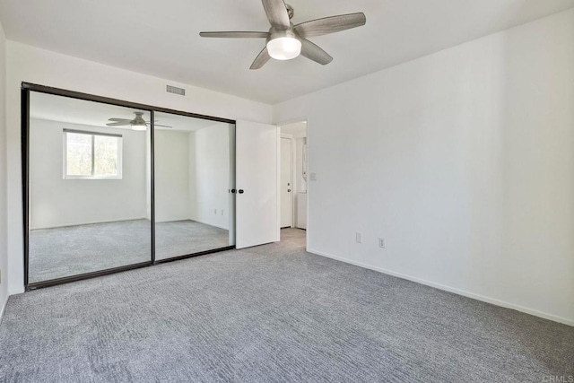 unfurnished bedroom featuring ceiling fan, carpet floors, visible vents, baseboards, and a closet