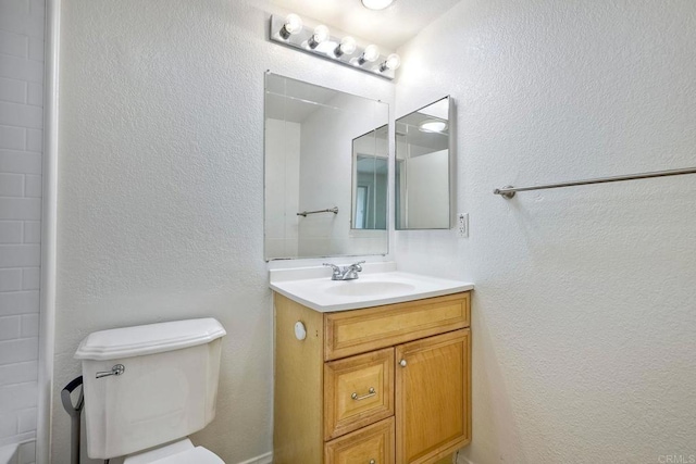 bathroom featuring a textured wall, vanity, and toilet