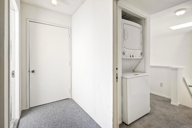 laundry room with carpet floors, laundry area, a textured ceiling, and stacked washer and clothes dryer