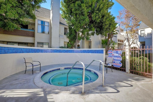 view of swimming pool with a hot tub and fence