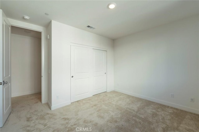 unfurnished bedroom featuring carpet floors, a closet, visible vents, and baseboards