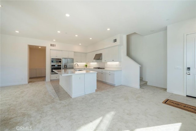 kitchen with light carpet, stainless steel fridge, an island with sink, under cabinet range hood, and a sink