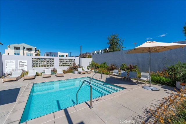 community pool with a patio and fence