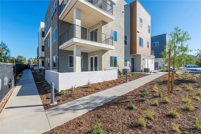 exterior space featuring central AC, fence, and stucco siding