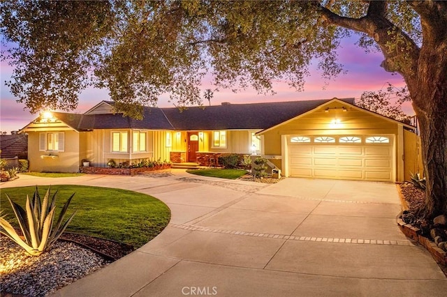 ranch-style house featuring a garage, concrete driveway, and a yard