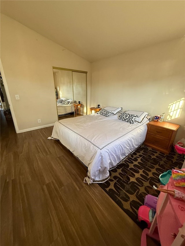 bedroom featuring vaulted ceiling, a closet, wood finished floors, and baseboards