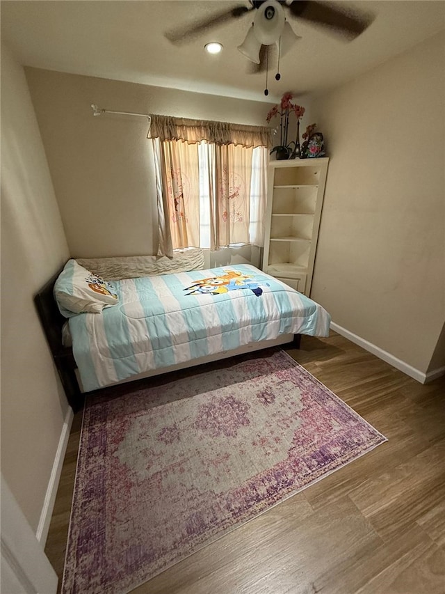 bedroom featuring ceiling fan, baseboards, and wood finished floors