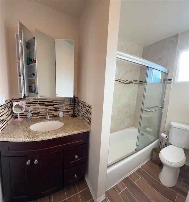 bathroom featuring tasteful backsplash, shower / bath combination with glass door, vanity, and toilet